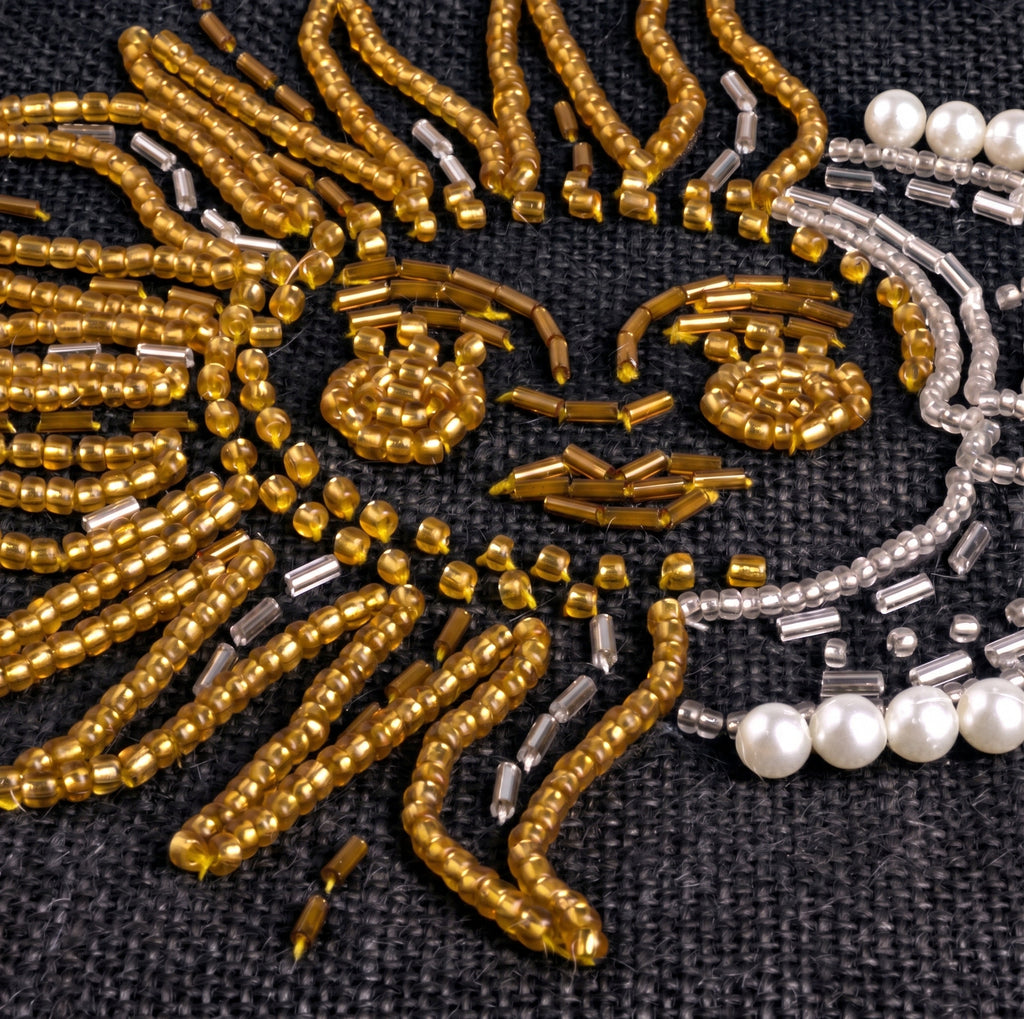 Close-up detail of the beaded sun and moon on the Petite Market Bag in Black: gold seed and bugle beads forming the sun's rays and face, silver beads and white pearls outlining the crescent moon on black jute